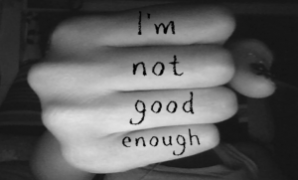 A hand shows the message "I'm not good enough" written on the fingers, conveying feelings of self-doubt and insecurity.