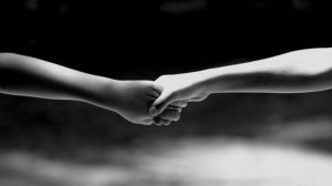 Two hands grasp each other firmly in a black and white image, symbolizing connection and support.