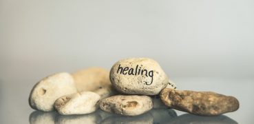 A collection of smooth stones with one prominently labeled "healing," symbolizing recovery and tranquility.