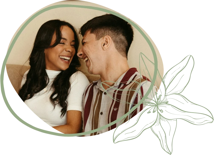 A couple sits closely on a couch, dressed casually, surrounded by a decorative green outline and floral design.