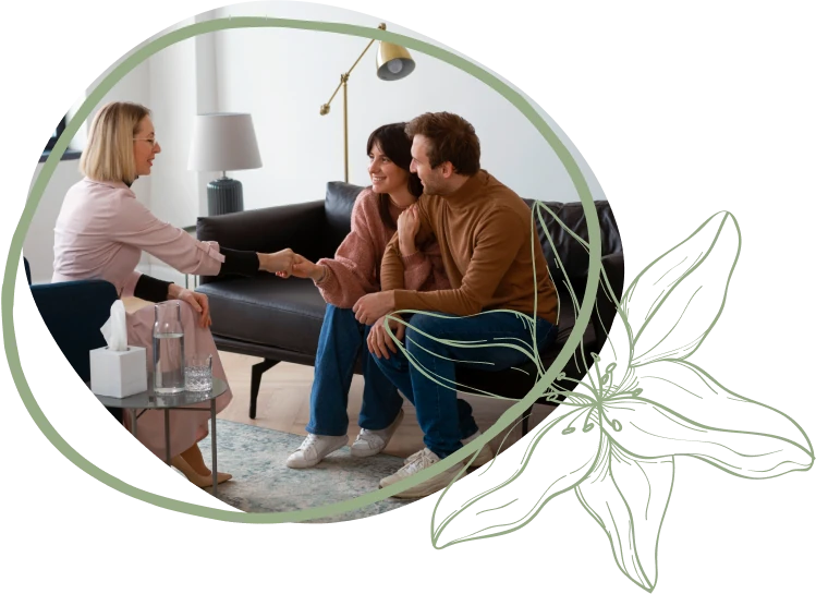 A therapist engages with a couple on a couch, discussing their relationship in a modern, well-lit living room setting.